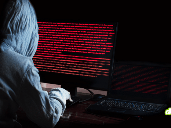 Image d'ambiance sombre montrant un attaquant manipulant du code informatique sur plusieurs moniteurs, symbolisant l'émergence du Vibeware et l'assistance de l'IA pour les cybercriminels.