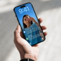Photographie d'une main tenant un iPhone dont l'écran de verrouillage iOS affiche plusieurs notifications, illustrant le nouveau système d'alerte urgente de sécurité déployé par Apple.