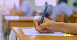 Main d'un étudiant rédigeant sa copie pour illustrer comment le piratage du portail scolaire Canvas paralyse les examens.