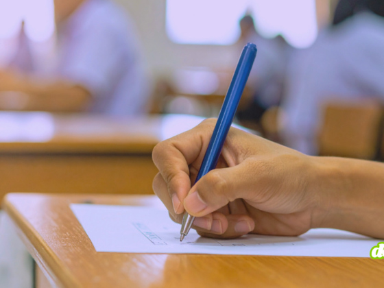 Main d'un étudiant rédigeant sa copie pour illustrer comment le piratage du portail scolaire Canvas paralyse les examens.
