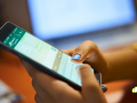 Une utilisatrice (ongles bleus) tient un smartphone affichant l'interface de Meta AI Incognito chat avec le clavier ouvert, illustrant l'utilisation du nouveau mode incognito de Meta. En arrière-plan flou, un ordinateur portable montre du code informatique, évoquant le contexte technique des experts DCOD analysant les paramètres de confidentialité et de chiffrement. Le logo dcod.ch est présent dans le