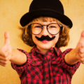 Enfant portant une fausse moustache et un chapeau melon pour illustrer la facilité de tromper une IA de vérification d'âge avec des accessoires rudimentaires.