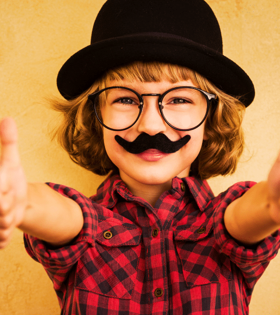 Enfant portant une fausse moustache et un chapeau melon pour illustrer la facilité de tromper une IA de vérification d'âge avec des accessoires rudimentaires.