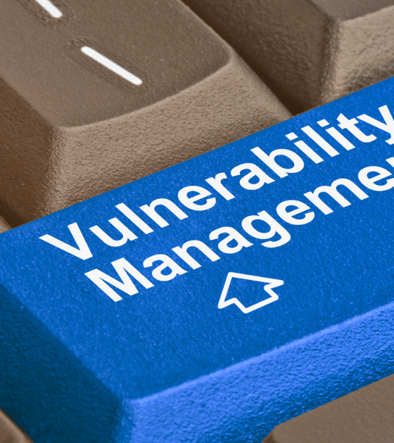 Gros plan sur un clavier d'ordinateur où la touche Entrée, de couleur bleue et marquée du logo d'un média tech, affiche l'inscription en blanc Vulnerability Management pour illustrer la divulgation de failles par un chercheur face à Microsoft.