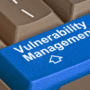 Gros plan sur un clavier d'ordinateur où la touche Entrée, de couleur bleue et marquée du logo d'un média tech, affiche l'inscription en blanc Vulnerability Management pour illustrer la divulgation de failles par un chercheur face à Microsoft.