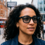 Gros plan d'une femme portant les lunettes connectées META Ray-Ban dans une rue animée.