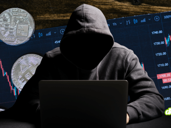 Individu anonyme en sweat à capuche devant un ordinateur, entouré de pièces de cryptomonnaies et de graphiques boursiers illustrant le contournement des sanctions.