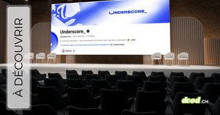 Une salle de conférence vide avec des sièges noirs au premier plan et une scène avec quatre chaises blanches à l'arrière-plan. Sur le grand écran de scène, on voit la page d'accueil YouTube de la chaîne 'Underscore_'