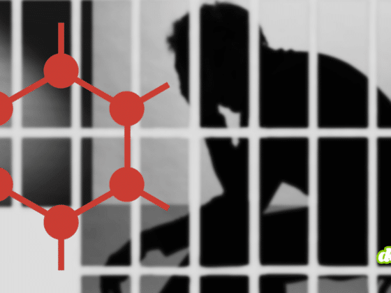 Logo rouge de GrapheneOS devant la silhouette d'un utilisateur derrière des barreaux de prison, illustrant les poursuites de la justice américaine.