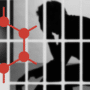 Logo rouge de GrapheneOS devant la silhouette d'un utilisateur derrière des barreaux de prison, illustrant les poursuites de la justice américaine.