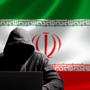 Silhouette sombre d'un pirate informatique en sweat à capuche devant un ordinateur portable, posant devant le drapeau national iranien.
