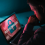 Un professionnel face à un ordinateur portable affichant un écran rouge avec un cadenas et l'inscription Ransomware, illustrant le risque pour les victimes de subir un second chantage.