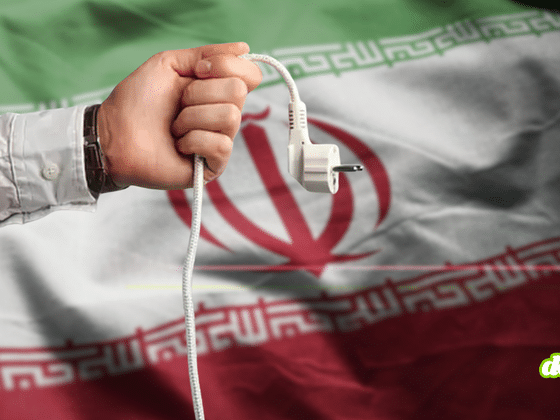 Texte alternatif (alt) : Une main débranche une prise électrique sur fond du drapeau de l'Iran, illustrant la cyberattaque contre une centrale électrique au Royaume-Uni.