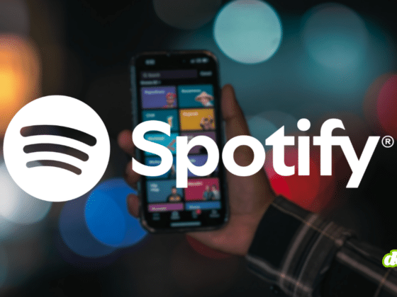 Logo Spotify et main tenant un smartphone affichant l'application, illustrant la décision de Spotify d'exclure les faux artistes IA de ses recommandations.