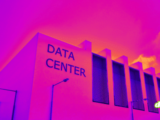 Façade moderne d'un centre de données sous un ciel aux teintes violettes et orangées, illustrant les infrastructures cloud.