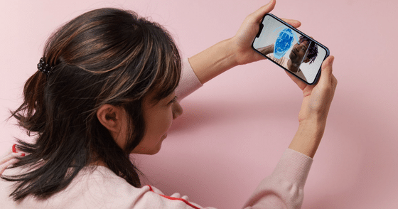 Une femme tient un smartphone affichant un visage analysé par un maillage numérique bleu, illustrant l'authentification et l'analyse visuelle par IA.