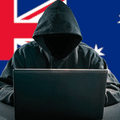 Une figure de pirate informatique encagoulée et anonyme est assise derrière un ordinateur portable ouvert, son visage dans l'ombre. En arrière-plan, le drapeau de l'Australie symbolise l'origine des suspects. Un petit logo circulaire 'dcod .CH' est visible dans le coin inférieur droit.