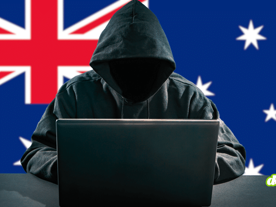 Une figure de pirate informatique encagoulée et anonyme est assise derrière un ordinateur portable ouvert, son visage dans l'ombre. En arrière-plan, le drapeau de l'Australie symbolise l'origine des suspects. Un petit logo circulaire 'dcod .CH' est visible dans le coin inférieur droit.
