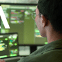 Développeur analysant du code informatique sur des écrans avec le sigle AI, illustrant l'audit automatisé