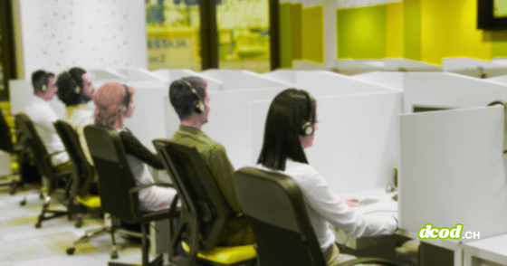 Opérateurs équipés de casques audio travaillant devant leurs écrans dans des box individuels au sein d'un centre d'appels.