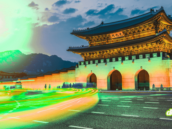 Porte Gwanghwamun éclairée de nuit à Séoul en Corée du Sud, avec des traînées lumineuses vertes et jaunes stylisées symbolisant les flux numériques et la cybersécurité.