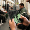 Gros plan sur un smartphone pliable tenu en main, montrant une fissure prononcée et un pli marqué au centre de l'écran intérieur éteint.