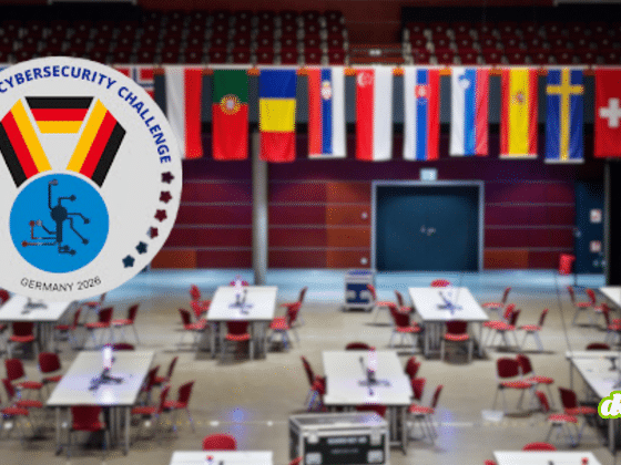 Vue générale de la grande salle de compétition de l'European Cybersecurity Challenge 2026 à Bochum avec les tables des délégations, surmontée des drapeaux des pays participants et du logo officiel de l'événement. — © Bochum Wirtschaftsentwicklung | Donna & der Blitz