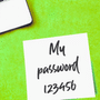 Note adhésive blanche posée à côté d'un clavier d'ordinateur portable sur fond vert, portant l'inscription manuscrite « My password 123456 ».