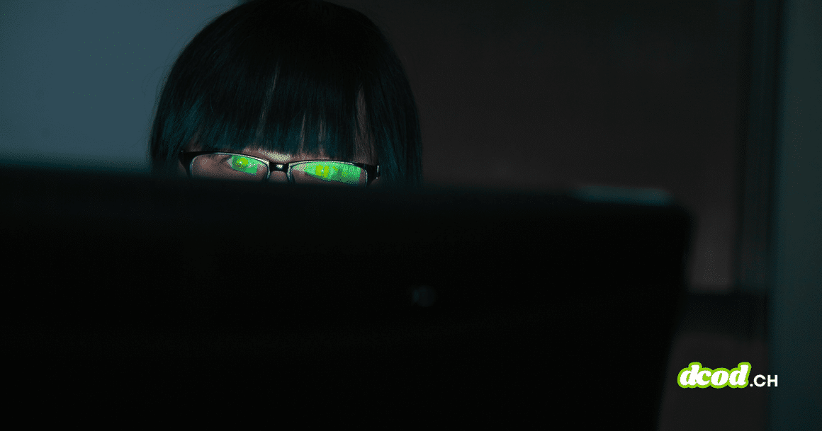 Pirate informatique observant un écran dans l'obscurité avec des reflets verts sur ses verres de lunettes, illustrant le vol de données du FBI par ShinyHunters.