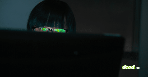 Pirate informatique observant un écran dans l'obscurité avec des reflets verts sur ses verres de lunettes, illustrant le vol de données du FBI par ShinyHunters.
